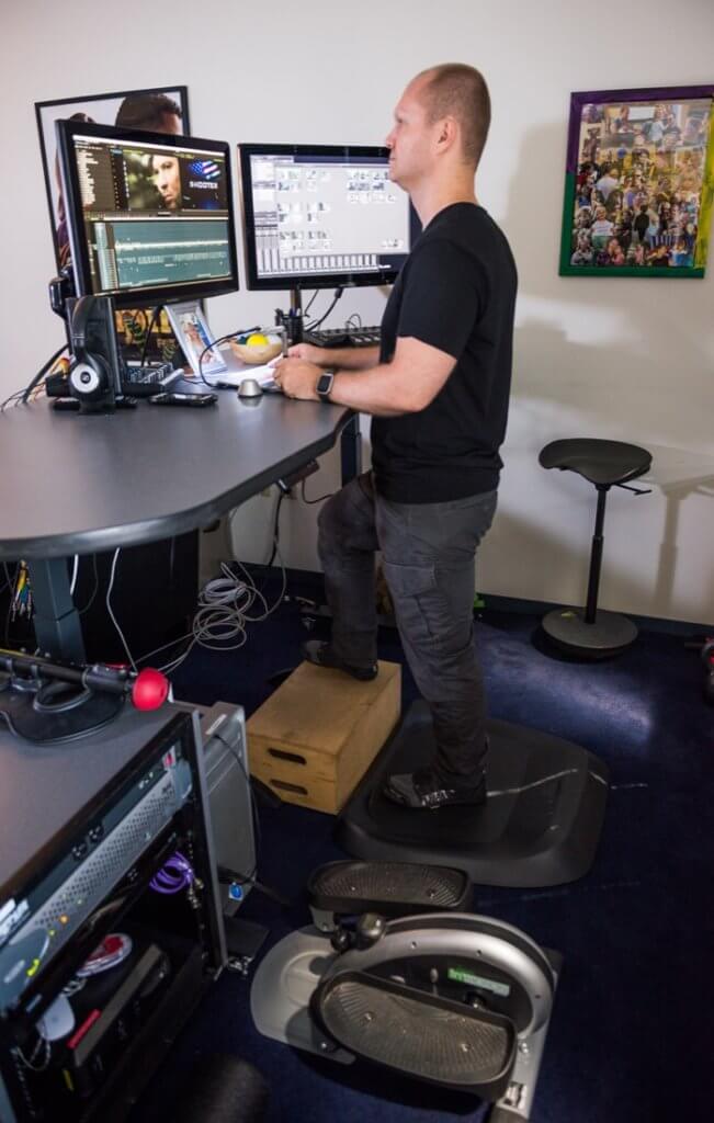 Zack standing on a topo mat at his height adjustable workstation
